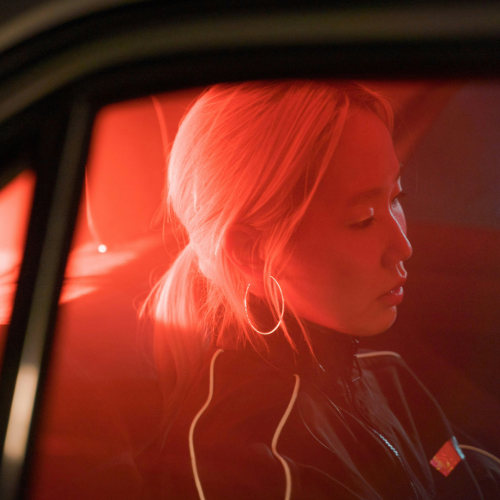 Young woman sitting in a car under red lighting, symbolizing modern consumer journeys, mobility trends, and audience context for marketing.
